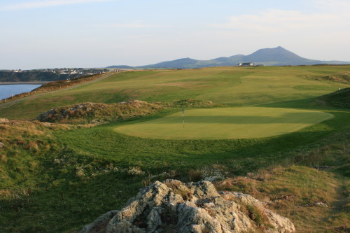 The view behind the 13th green and fairway at Nefyn & District Golf Club, Wales, with the clubhouse in the distance.