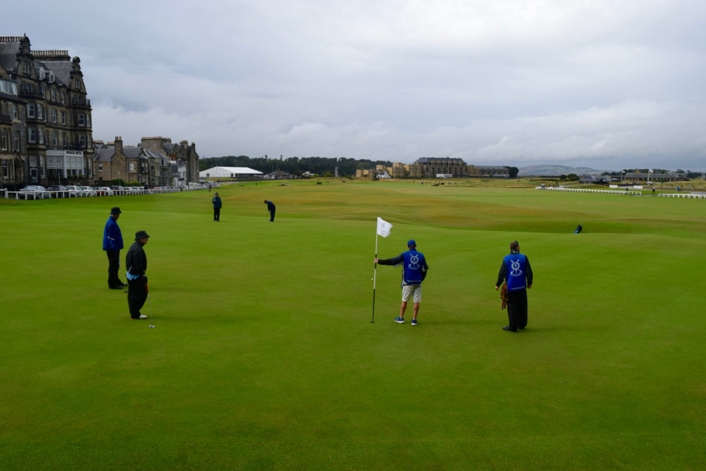 Golfers and caddies on the 18th green at the Old Course at St. Andrews.