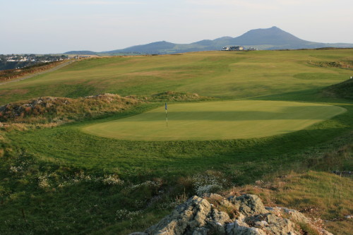 The 13th green at Nefyn & District Golf Club in North Wales, with the clubhouse in the center distance.