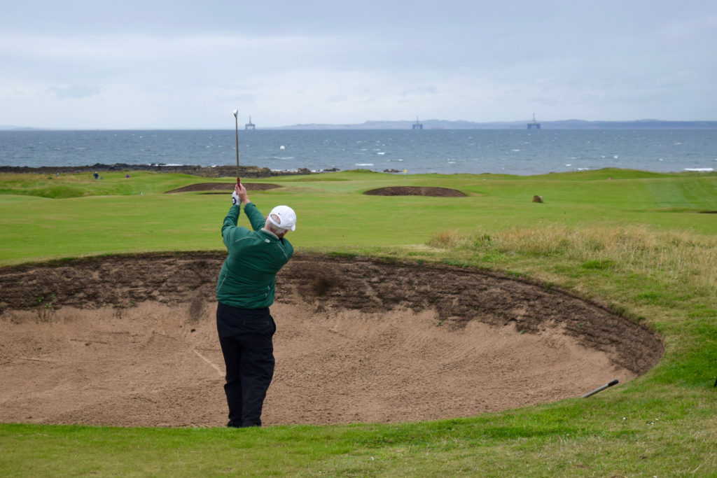 Tom Cade plays from a bunker at Elie Links toward the sixth green and the Firth of Forth.